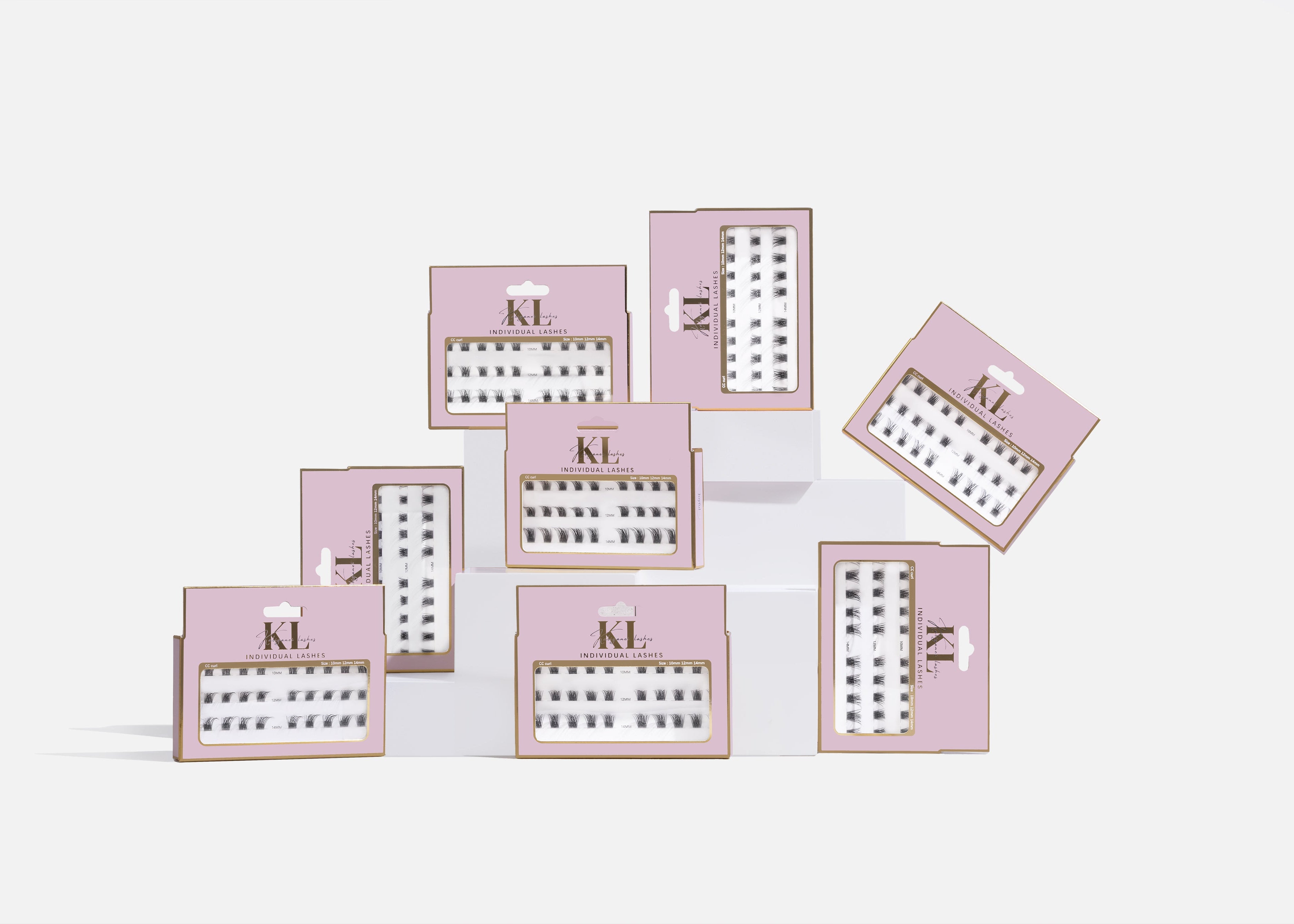 The Refined Lash Artistry Collection individual lash clusters in pink premium packaging displayed on white platform